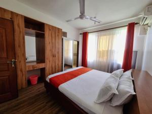 蒙巴萨H20 APARTMENTS NYALI的一间卧室配有床和红色窗帘的窗户