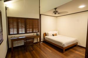 秾莎Nongsa Village的一间卧室配有一张床、一张桌子、一张床和一个窗户。