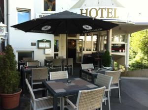 雷姆沙伊德奥堡罗酒店的一间带桌椅和遮阳伞的餐厅