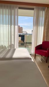 卡尔佩AR Diamante Beach & SPA Hotel 4 SUP的一间卧室配有一张床、一张红色椅子和一个窗户