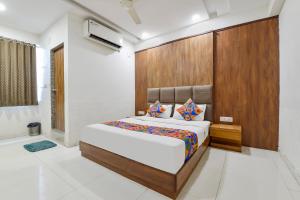 NarodaFabHotel Maan Palace的一间卧室配有一张大床和木制床头板