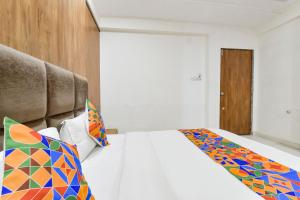 NarodaFabHotel Maan Palace的卧室配有白色的床和色彩缤纷的枕头