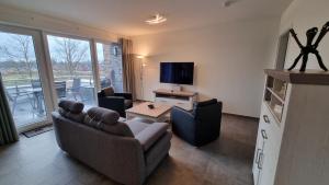 文迪施里茨Park-Apartment Scharmützelsee Wohnung 13的客厅配有沙发、椅子和电视