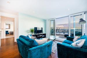 伦敦Austin David Apartments ExCeL的客厅配有2张蓝色沙发和1台电视