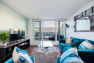 伦敦Austin David Apartments ExCeL的客厅配有蓝色的沙发和电视