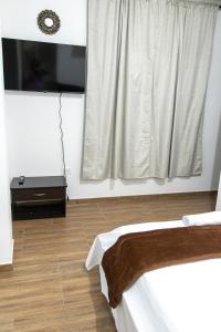 佩雷拉Hotel Maranta的客房设有一张床和带电视的窗户。
