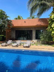 班帕那普兰Chill Villa的一个带2把躺椅的游泳池以及1栋房子