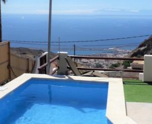 圣克鲁斯-德特内里费Nueva Casa rural piscina privada的坐在游泳池旁椅子上的人