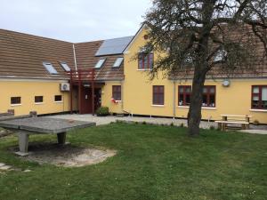 OnsbjergPension Stenvang的黄色的建筑,带有野餐桌和一棵树