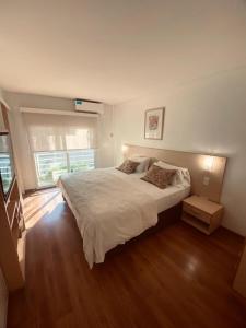 罗萨里奥里奥格兰德公寓式酒店的卧室配有一张白色的大床,铺有木地板