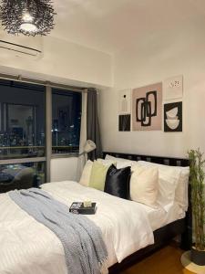 马尼拉The Serene Escape Rockwell Makati City View 1BR的一间卧室配有一张带白色床单的床和一扇窗户。