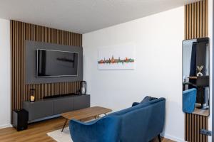 德累斯顿Sunnybelle Appartements Dresden I的客厅配有2把蓝色椅子和电视