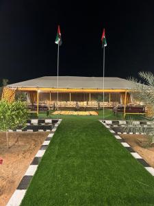 Al Khatimمزرعة واستراحة الجوري的草坪顶部有两面旗帜的建筑