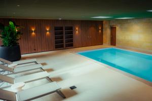 法尔肯堡帕拉姆酒店的游泳池位于带椅子和桌子的房间