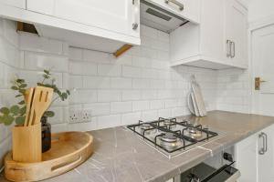 伦敦Wembley Hububb Stay的厨房配有白色橱柜和炉灶烤箱。