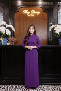 顺化Thuy Duong Boutique Hotel Hue的站在柜台前身穿紫色衣服的女人