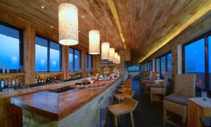 博卡拉Sarangkot Mountain Lodge的餐厅设有酒吧,配有椅子和窗户