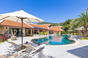 拉威海滩Villa Carlos, Luxury 7 BDR Private Pool Villa, Baan Bua Nai Harn, Phuket的一个带椅子和遮阳伞的度假村游泳池