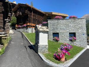 采尔马特Chalet Coral und Zermatter Stadel的一座石头建筑,前面有鲜花