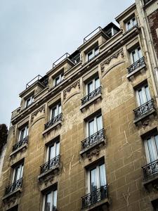 巴黎Hotel de Flore - Montmartre的一座高高的砖砌建筑,设有窗户和阳台
