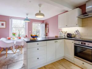 Wingfield2 Bed in Bath 81298的厨房设有粉红色的墙壁、白色的橱柜和一张桌子