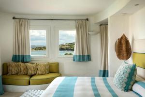 切尔沃港Romazzino, A Belmond Hotel, Costa Smeralda的一间卧室设有床、窗户和沙发