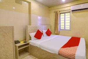 加尔各答Hotel Royal Inn的一间卧室配有一张带红色枕头的床和一扇窗户