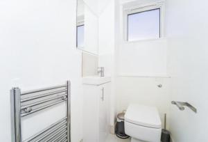 伦敦Spacious modern family bedroom in Central London的白色的浴室设有卫生间和窗户。