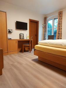 瓦伦多夫Gästehaus Niemerg的一间卧室配有一张床和一张书桌及电视