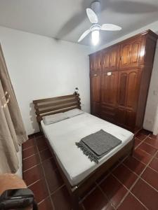 瓜鲁雅Apartamento Guaruja Enseada的一间卧室配有一张床和一个木制橱柜