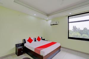 坎普尔OYO Flagship Shree Shyam Kripa Hotel And Restaurant的一间卧室配有一张带红色枕头的床和一扇窗户