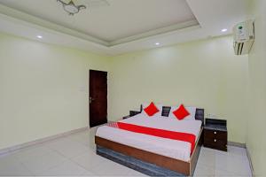 坎普尔OYO Flagship Shree Shyam Kripa Hotel And Restaurant的一间卧室配有一张带红色枕头的大床