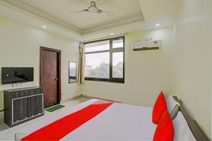 坎普尔OYO Flagship Shree Shyam Kripa Hotel And Restaurant的一间卧室设有一张床、一台电视和一个窗口。