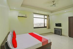 坎普尔OYO Flagship Shree Shyam Kripa Hotel And Restaurant的一间卧室配有一张带红色枕头的床和电视。