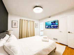 洛杉矶Relaxing 6 BR Oasis with Pool - Lou1的白色卧室设有一张床和墙上的电视