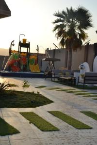 Ash Shishahشاليهات ميرامار مكة الحسينية的一个带长椅、桌子和棕榈树的庭院