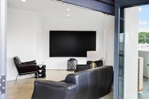 奥克兰Freeman Escape with garage parking的客厅配有黑色真皮沙发和平面电视。