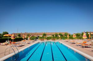 瓦达ISA-Residence with swimming-pool in Vada, apartments with air conditioning and private outdoor area的一个带椅子和遮阳伞的大型游泳池