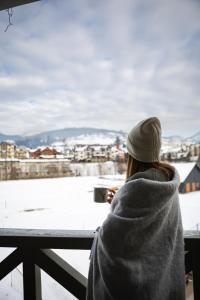 布克维扎提硕克酒店的一位身着毯子的女人,看着一个雪覆盖的城市的窗户