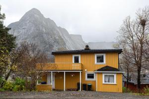 雷讷Cozy House By The Fjord In The Heart Of Lofoten的一座黄色房子,后面有山