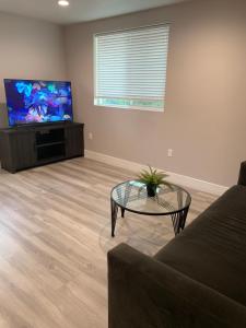 洛杉矶PRIVATE ROOM IN NEW APPARTMENT WITH FULL BATH的客厅配有沙发、桌子和平面电视。