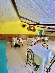 Ceará-MirimPousada Elpirata Sidney的餐厅设有桌椅和黄色的墙壁
