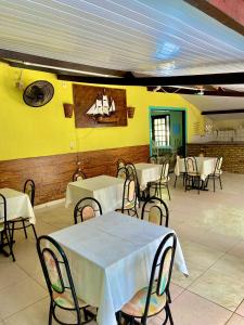 Ceará-MirimPousada Elpirata Sidney的餐厅设有桌椅和黄色的墙壁