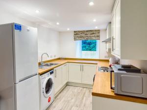 CrayWester Caiplich - Uk30261的厨房配有白色橱柜、洗衣机和烘干机