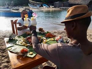 Puerto LimónECOHOTEL LILI的两人坐在餐桌旁,在沙滩上吃点东西