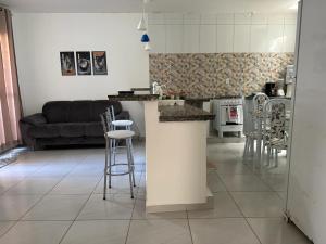 盖比姆Casa Cantinho da Família - Praia de Guaibim -的厨房以及带柜台和凳子的客厅。