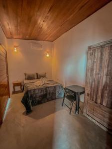 加利纽斯Chalé Galo Preto的一间卧室设有一张床铺和一张桌子,拥有木制天花板