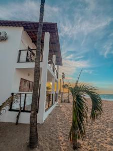 加利纽斯Chalé Galo Preto的海滩上的白色房子,棕榈树