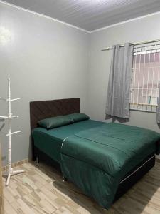 佩尼亚Casa de praia em Penha的一间卧室配有一张带绿色床单的床和一扇窗户。