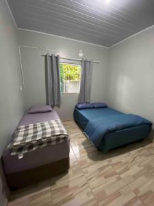 佩尼亚Casa de praia em Penha的两张床位于带窗户的房间内